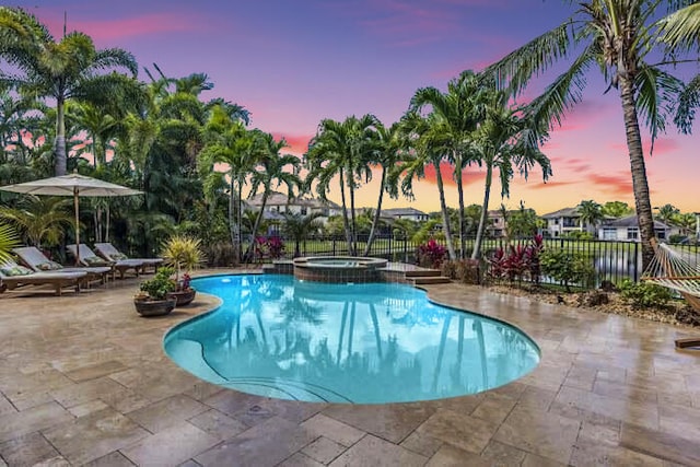 pool at dusk featuring an in ground hot tub and a patio area