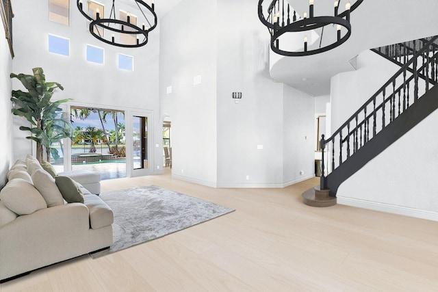 living room with a chandelier, light wood-type flooring, and a towering ceiling