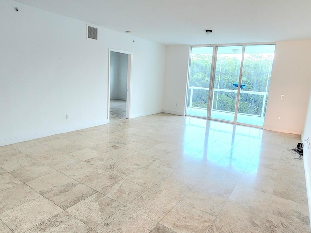 empty room with a wall of windows and light tile floors