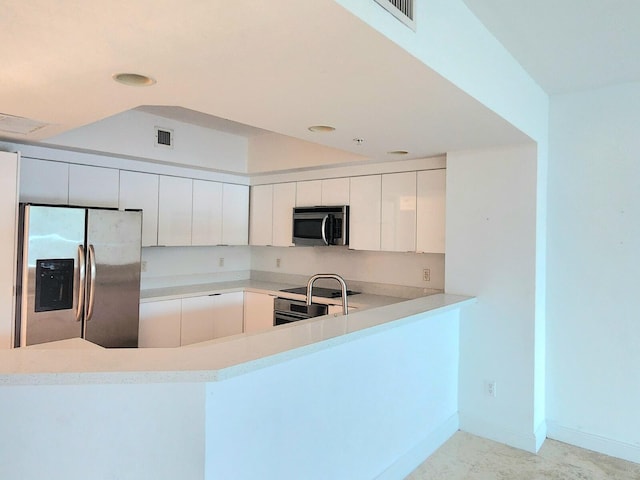 kitchen with kitchen peninsula, appliances with stainless steel finishes, and white cabinets