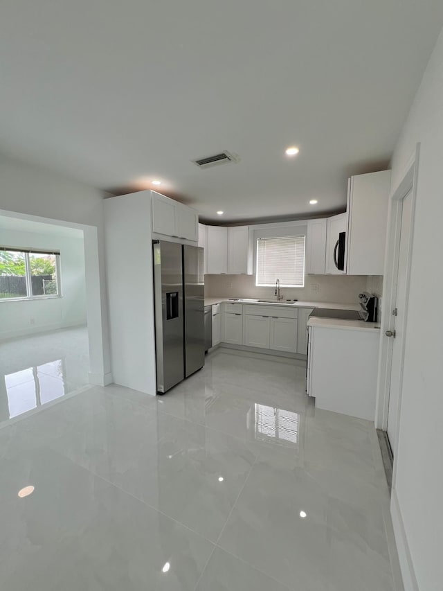 kitchen with appliances with stainless steel finishes, sink, and white cabinets