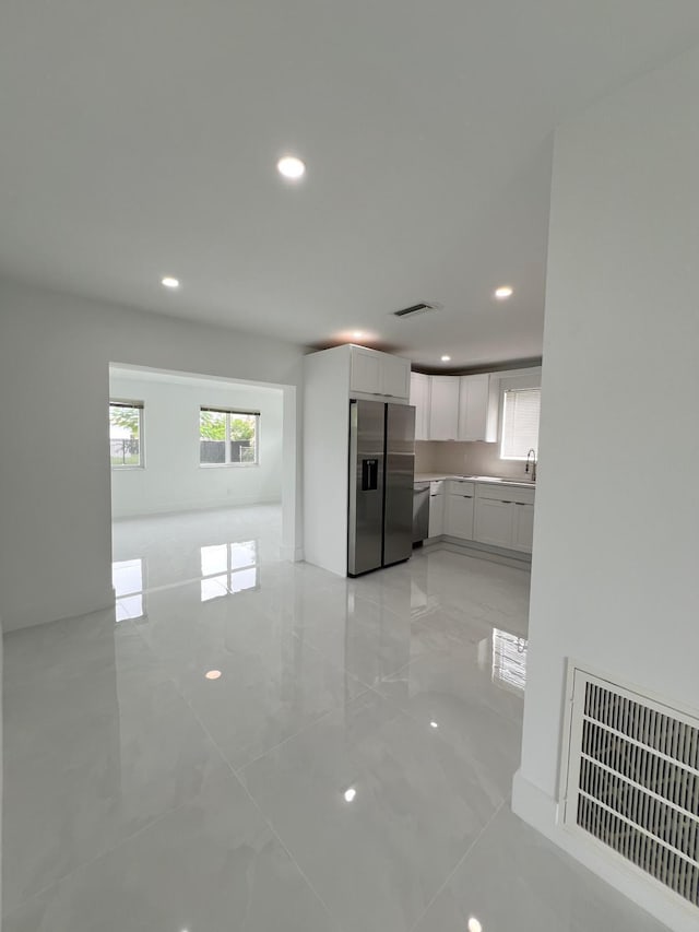 kitchen featuring stainless steel fridge, sink, and white cabinets