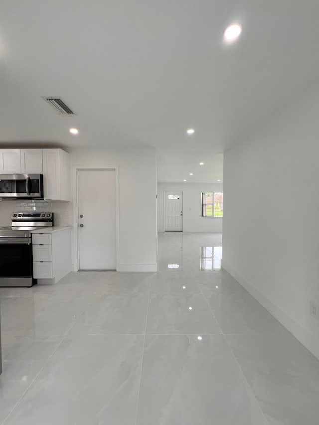 kitchen featuring white cabinets, backsplash, and appliances with stainless steel finishes