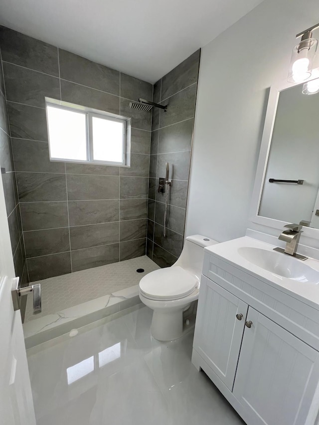 bathroom with vanity, tile patterned floors, toilet, and tiled shower