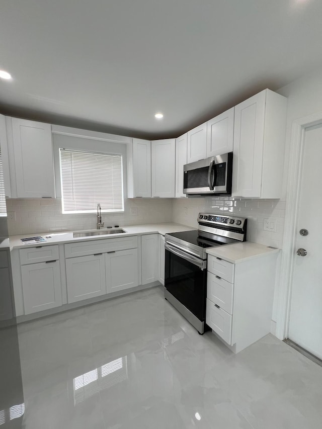 kitchen featuring white cabinetry, appliances with stainless steel finishes, tasteful backsplash, and sink