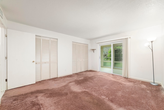 unfurnished bedroom with two closets, access to outside, and carpet flooring