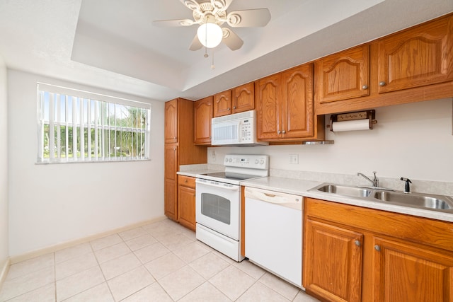 kitchen featuring white appliances, light tile floors, sink, a raised ceiling, and ceiling fan