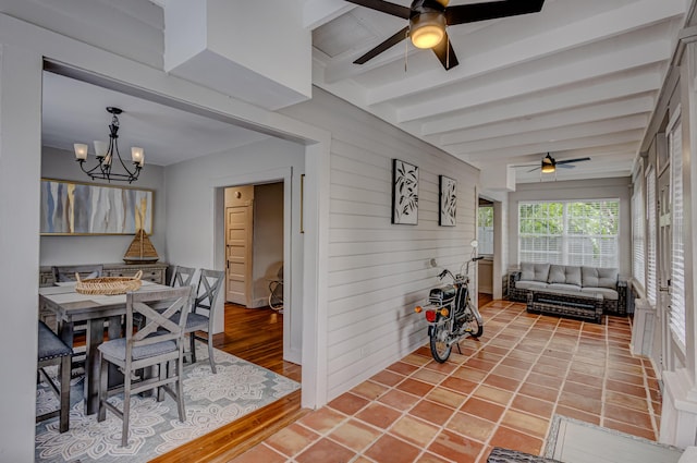 dining space with beamed ceiling, wood-type flooring, and ceiling fan with notable chandelier