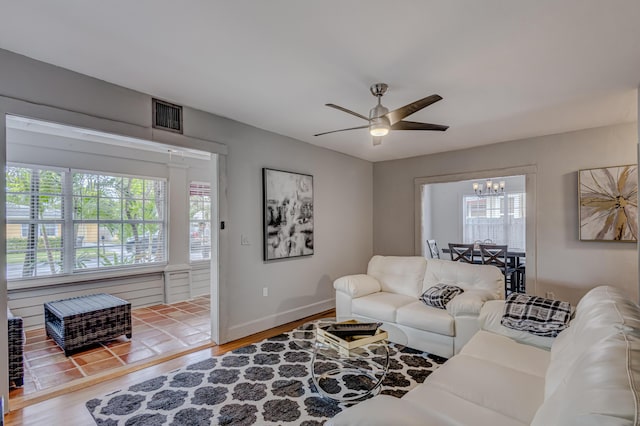 living room featuring hardwood / wood-style floors, ceiling fan with notable chandelier, and a healthy amount of sunlight