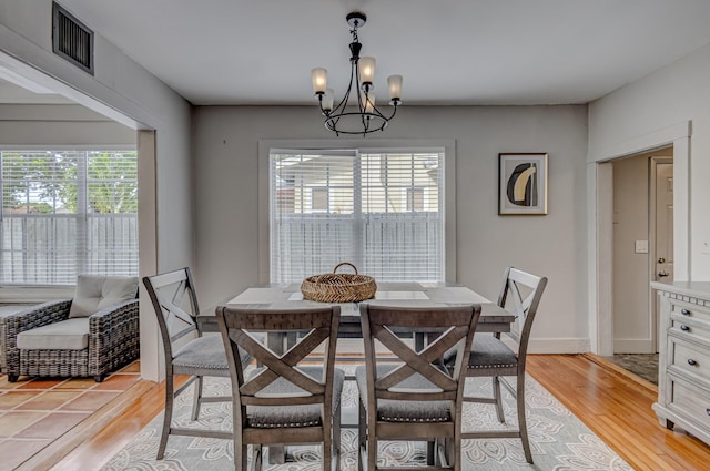 dining space featuring light wood-type flooring, a wealth of natural light, and an inviting chandelier