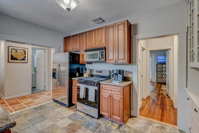 kitchen featuring appliances with stainless steel finishes, light hardwood / wood-style floors, and light stone counters