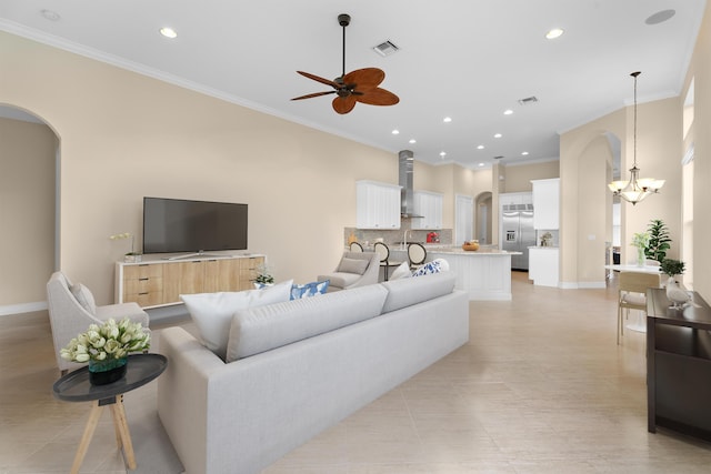 tiled living room with ceiling fan with notable chandelier and ornamental molding