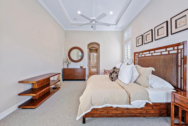 carpeted bedroom with ceiling fan, ornamental molding, connected bathroom, and a tray ceiling