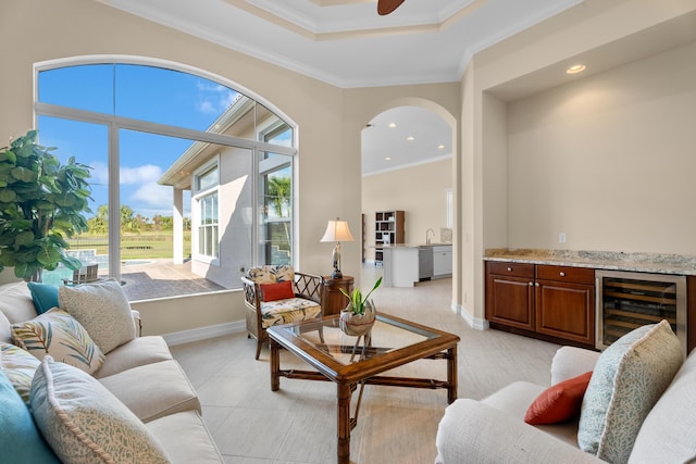 living room with a raised ceiling, crown molding, a towering ceiling, and ceiling fan with notable chandelier