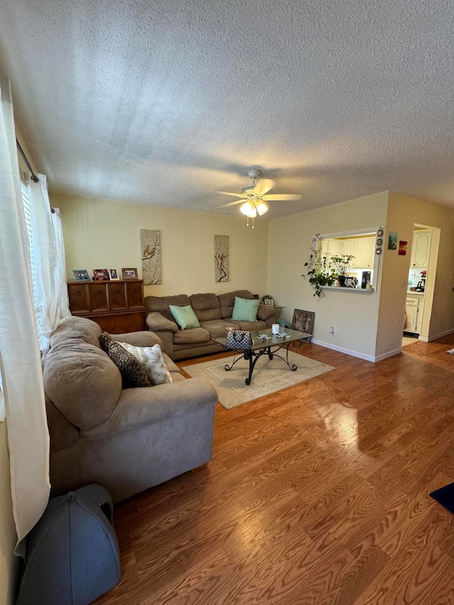 living room featuring hardwood / wood-style floors, ceiling fan, and a textured ceiling