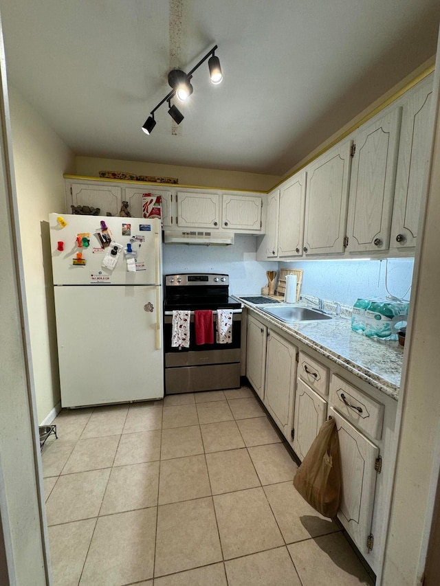 kitchen featuring stainless steel range with electric cooktop, white refrigerator, track lighting, light tile floors, and sink