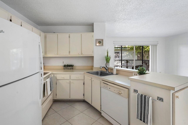 kitchen with cream cabinetry, kitchen peninsula, white appliances, and sink