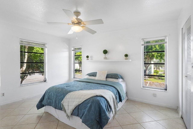 bedroom featuring light tile patterned floors, a textured ceiling, a closet, and ceiling fan