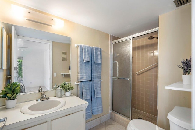 bathroom featuring tile patterned flooring, vanity, toilet, and walk in shower