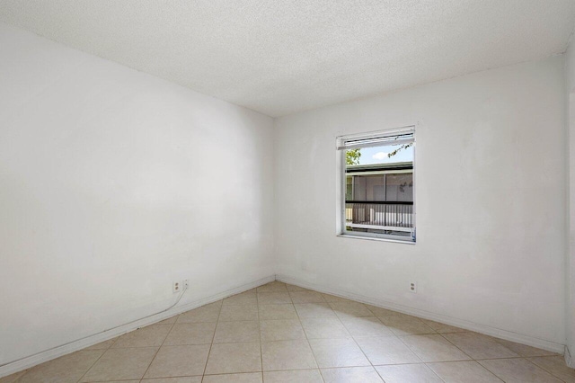 spare room featuring light tile patterned floors and a textured ceiling