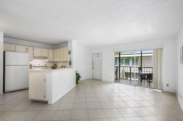 kitchen featuring a textured ceiling, cream cabinets, light tile patterned flooring, and white appliances