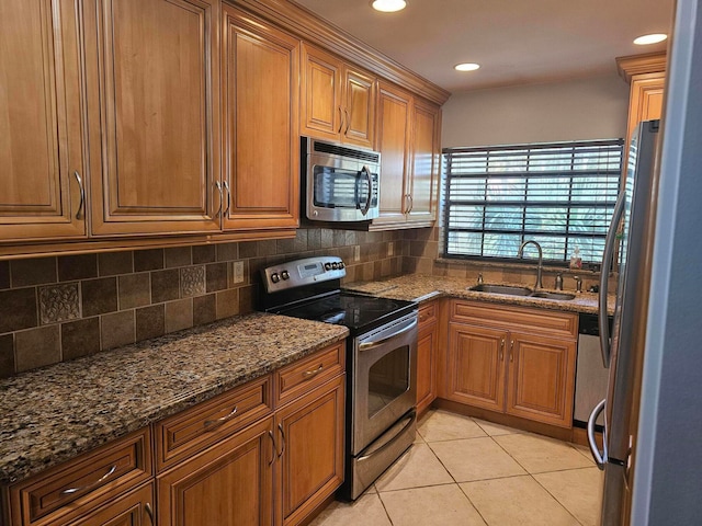 kitchen featuring decorative backsplash, light tile patterned floors, dark stone counters, sink, and stainless steel appliances