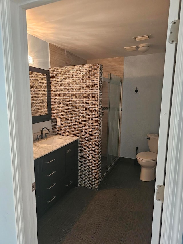 bathroom featuring lofted ceiling, toilet, a shower with shower door, vanity, and tile walls