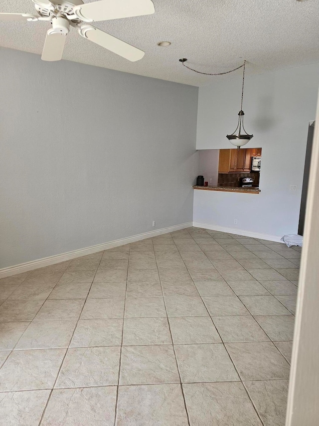 empty room featuring a textured ceiling, light tile patterned flooring, and ceiling fan