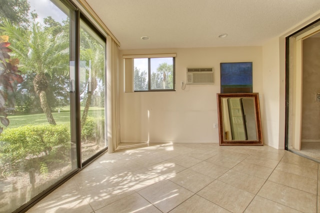 empty room featuring a wall mounted air conditioner, light tile patterned floors, and a textured ceiling