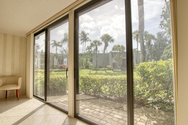 doorway to outside with expansive windows, a textured ceiling, and light tile patterned floors