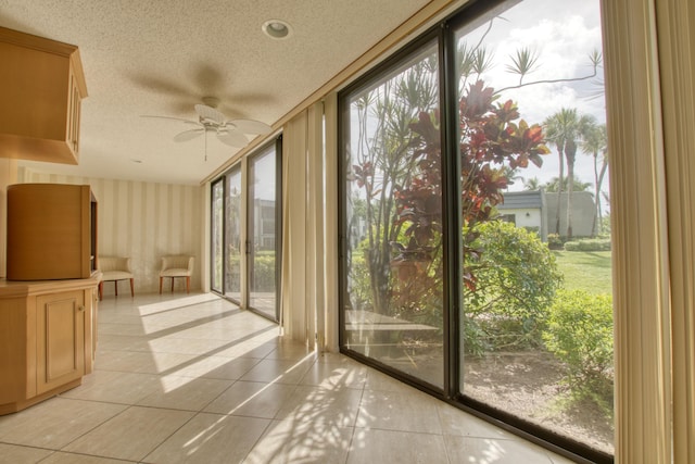 doorway to outside featuring ceiling fan, a wall of windows, a textured ceiling, and light tile patterned floors