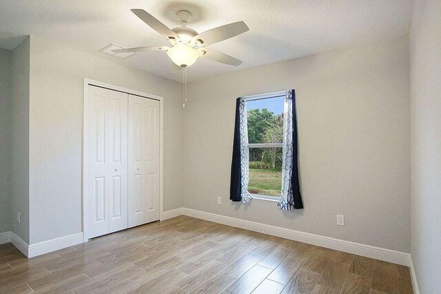 unfurnished bedroom with ceiling fan, light hardwood / wood-style floors, and a closet