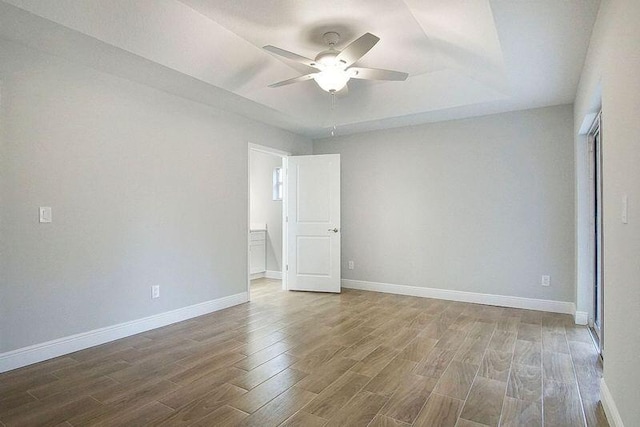 spare room with ceiling fan, a tray ceiling, and hardwood / wood-style flooring