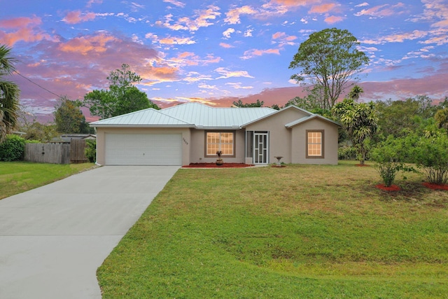 single story home with metal roof, an attached garage, concrete driveway, stucco siding, and a front lawn