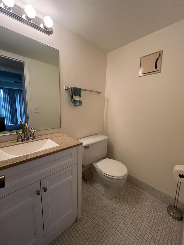 bathroom with tile flooring, toilet, and vanity