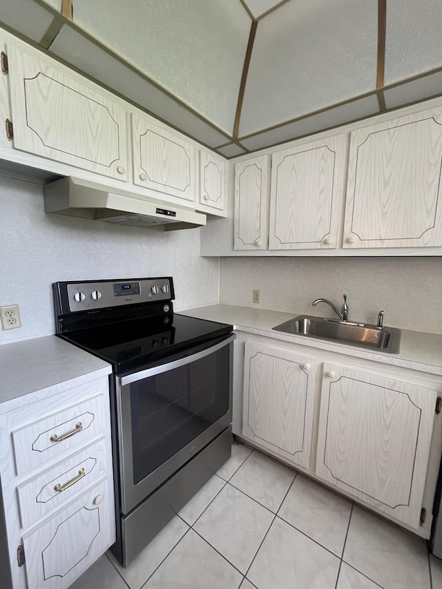 kitchen featuring white cabinets, sink, light tile flooring, and stainless steel electric stove