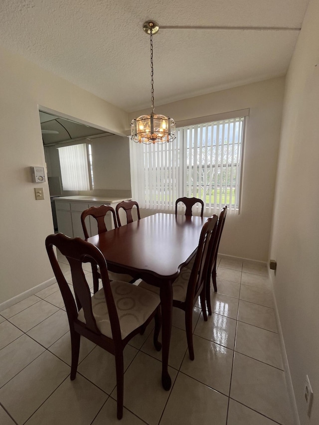 tiled dining room featuring a notable chandelier and a textured ceiling