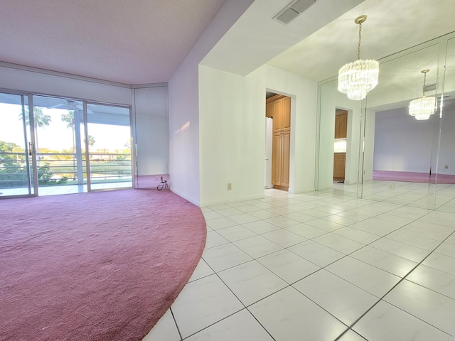 carpeted empty room featuring a notable chandelier