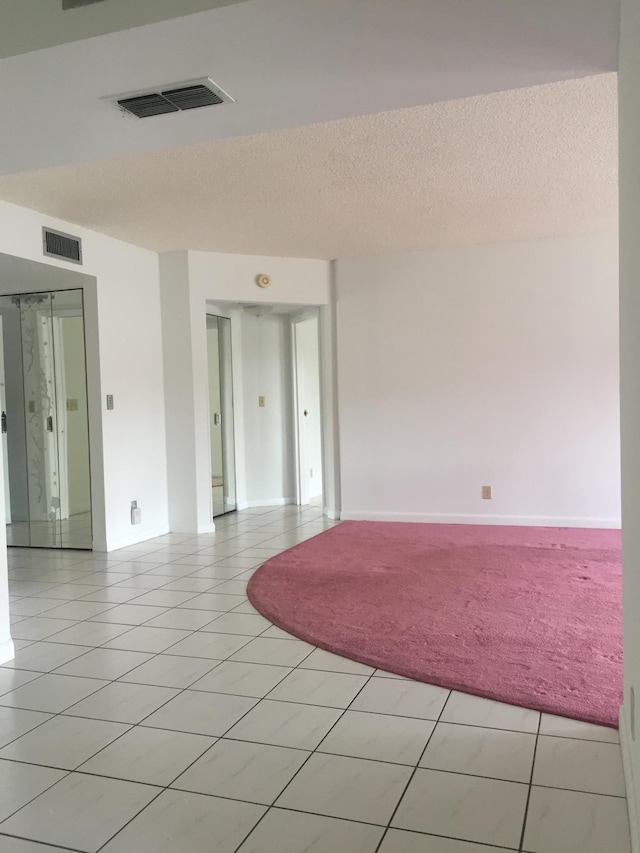 empty room with a textured ceiling and light tile floors