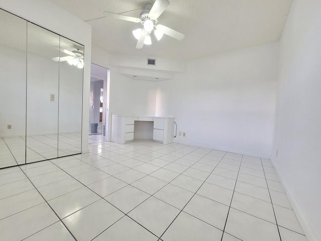 tiled empty room with a textured ceiling and ceiling fan