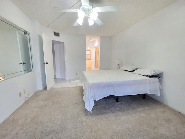 bedroom with light colored carpet, ceiling fan, a textured ceiling, and ensuite bathroom