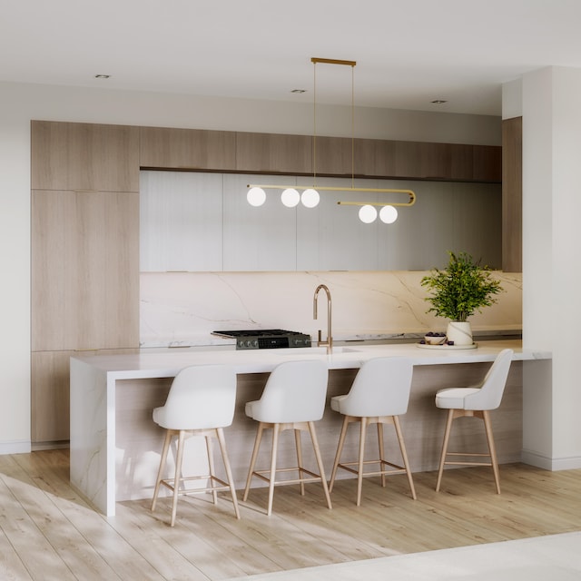 kitchen with a breakfast bar, sink, decorative backsplash, decorative light fixtures, and light hardwood / wood-style floors