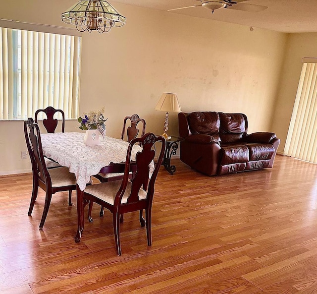 dining space featuring ceiling fan with notable chandelier and hardwood / wood-style floors