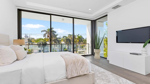 bedroom with access to exterior, a wall of windows, and hardwood / wood-style flooring