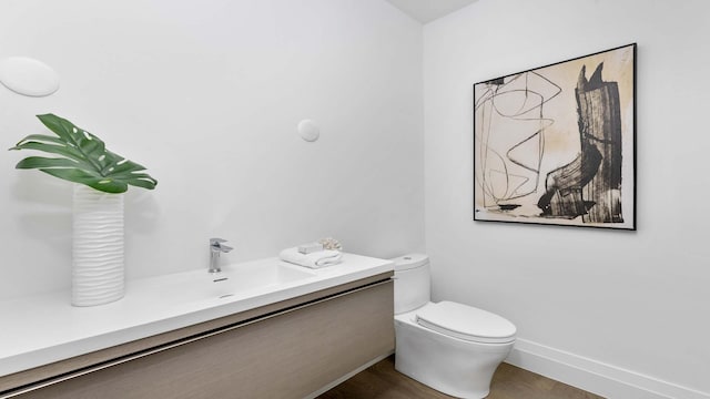 bathroom with hardwood / wood-style floors, vanity, and toilet