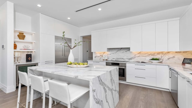 kitchen featuring white cabinetry, backsplash, hardwood / wood-style floors, and stainless steel appliances