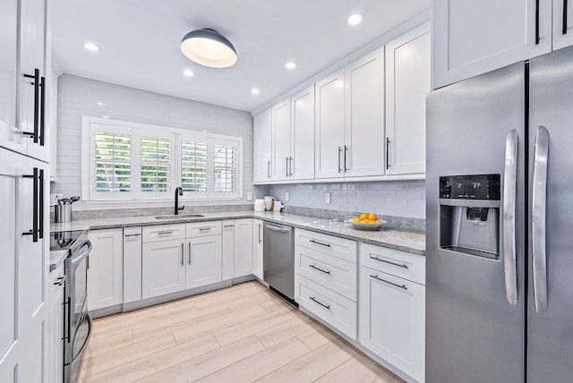 kitchen featuring light hardwood / wood-style flooring, stainless steel appliances, tasteful backsplash, white cabinetry, and sink