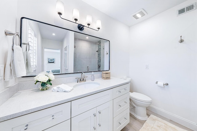 bathroom featuring tiled shower, vanity with extensive cabinet space, and toilet