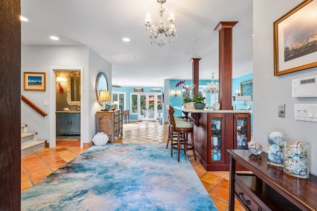 interior space featuring decorative columns, a notable chandelier, and tile flooring