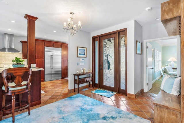 entrance foyer with decorative columns, light tile flooring, and an inviting chandelier